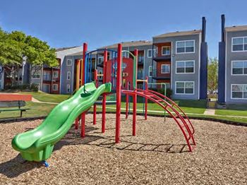 A green slide in a playground with a red frame.